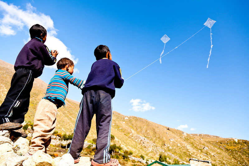 Child on rural area enjoying their kites on open sky