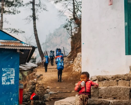 Porters Of Khumbu Walk By A Local Village Of Khumbu